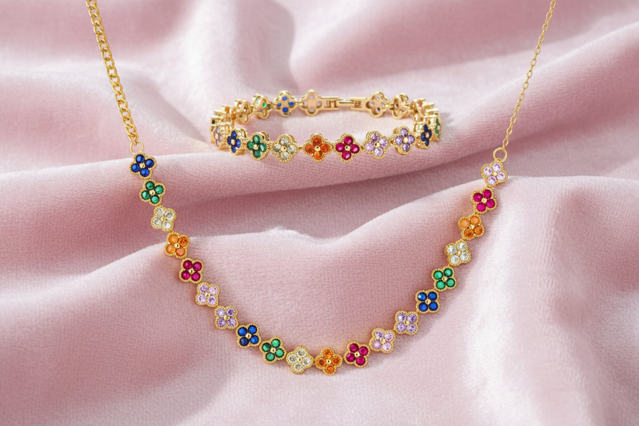 Colorful four-leaf clover jewelry set with rainbow cubic zirconia stones in gold-plated setting on white background