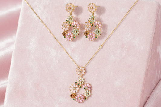 14K gold plated jewelry set with pink and green cubic zirconia flowers arranged in wreath design on cream background