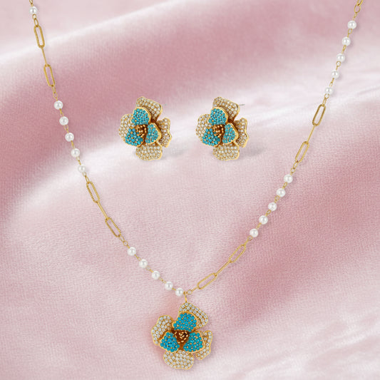 14K gold-plated floral jewelry set with blue cubic zirconia centers and pearl chain details on white background.
