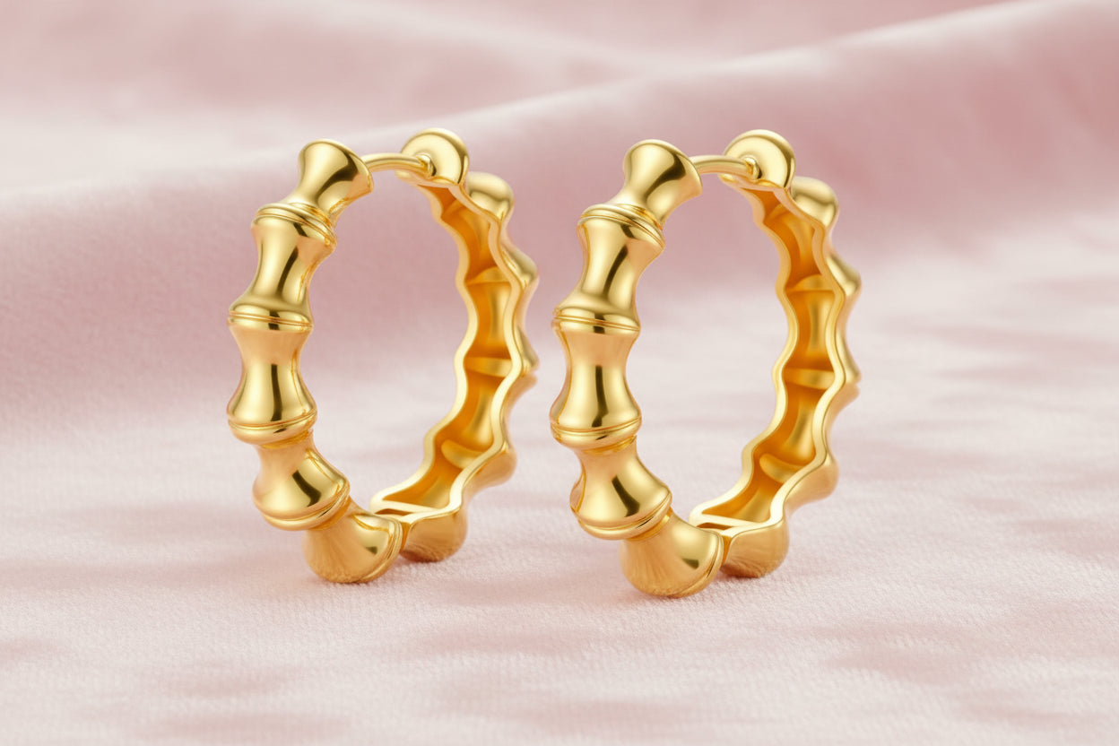Close-up of gold-plated sterling silver hoop earrings with bamboo-inspired segmented design on white background.