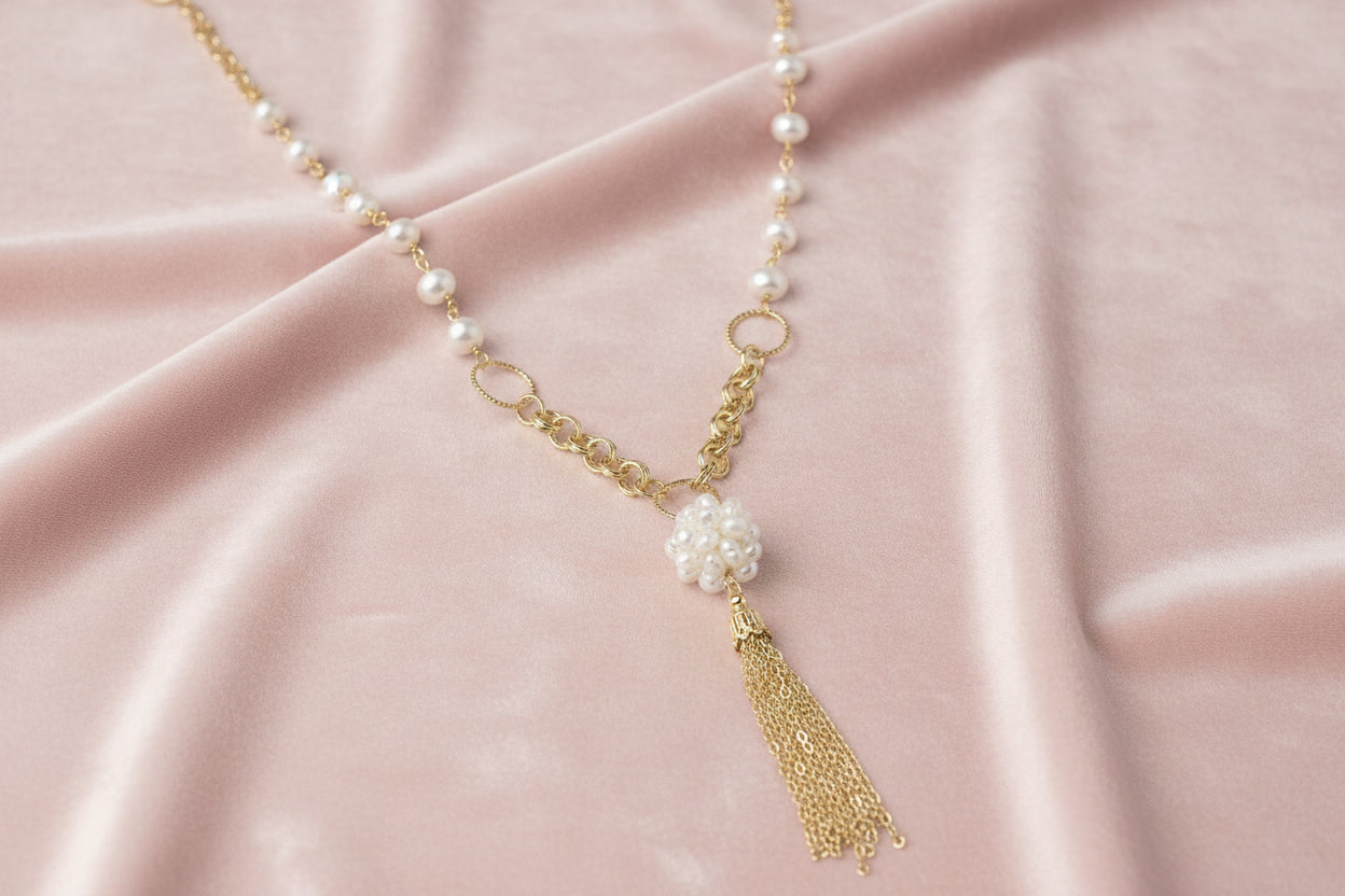 Long gold-plated necklace with freshwater pearls, chunky chain links, and flowing tassel pendant
