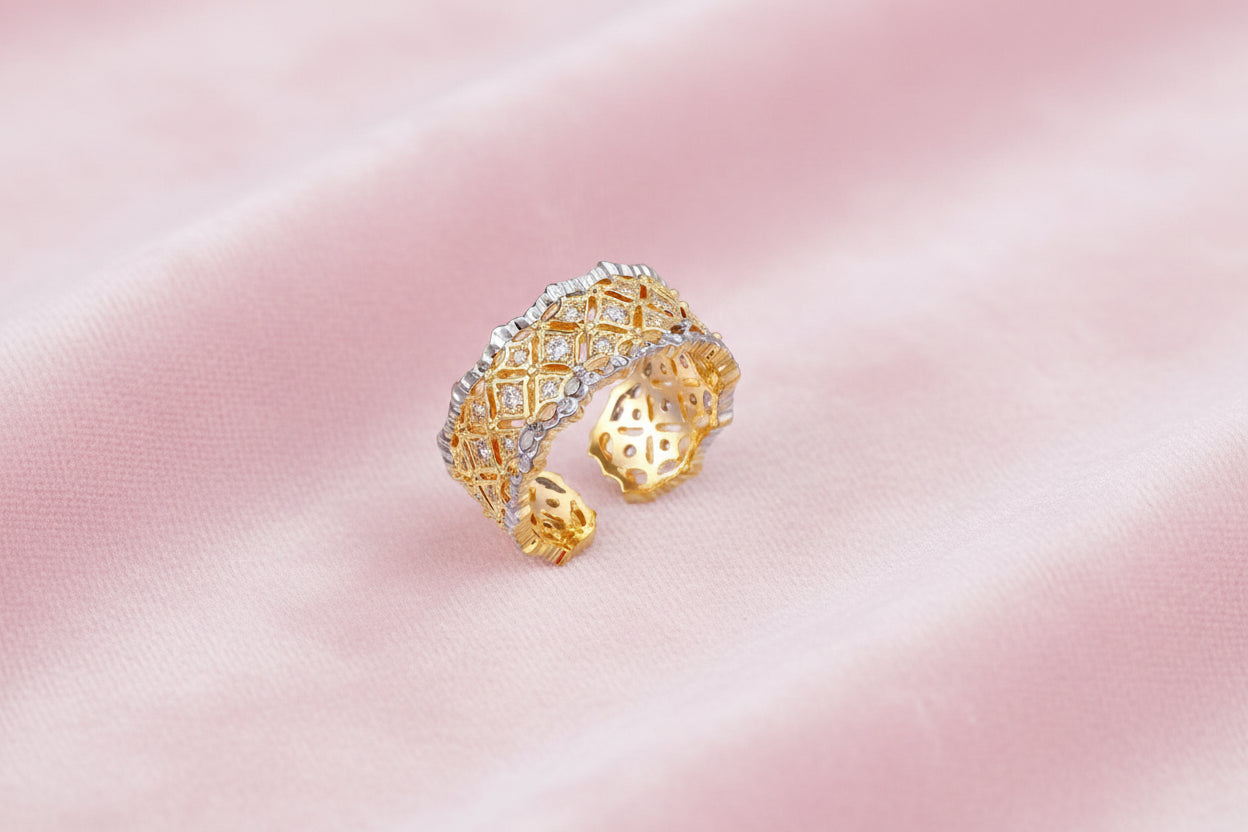Two-tone ring with geometric lattice pattern in gold and silver finish with crystal accents on beige background