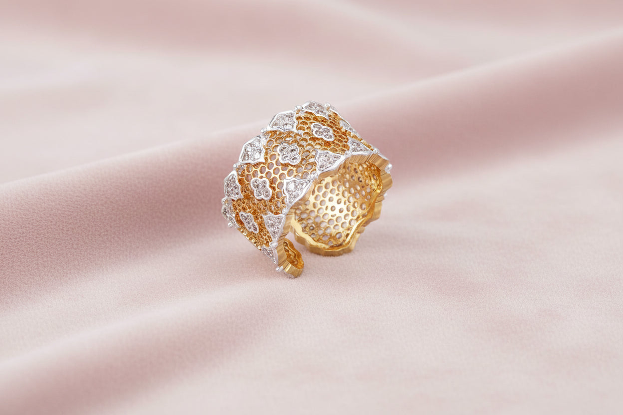 Two-tone gold and silver lattice ring with clover pattern and crystal accents on white background