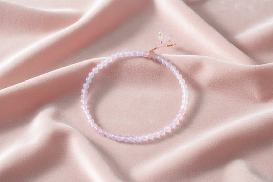 Double-wrap lavender beaded bracelet with rose quartz, pearls, gold vermeil charm and pink tassel on white background.