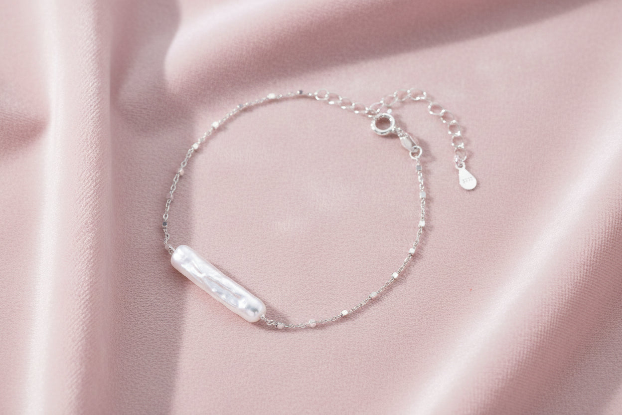 Minimalist bracelet with iridescent baroque pearl on rhodium-plated sterling silver chain against cream background