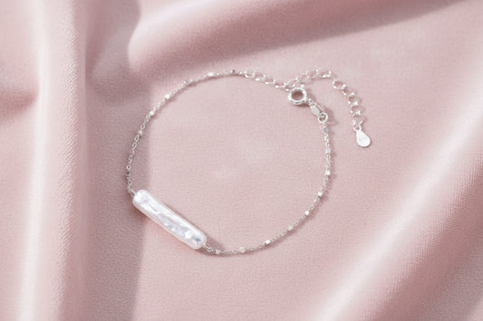 Minimalist bracelet with iridescent baroque pearl on rhodium-plated sterling silver chain against cream background