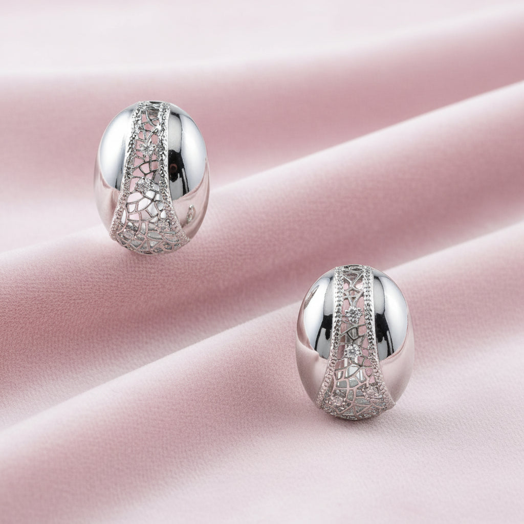 White gold-plated dome hoop earrings with geometric lattice pattern and zirconia stones on cream background