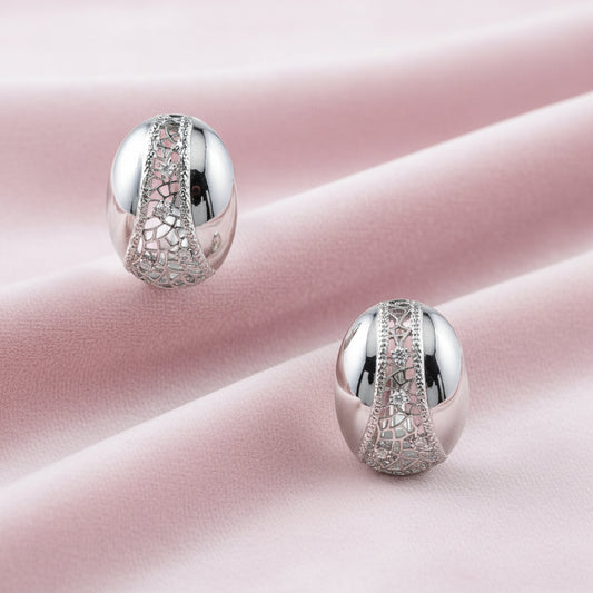 White gold-plated dome hoop earrings with geometric lattice pattern and zirconia stones on cream background
