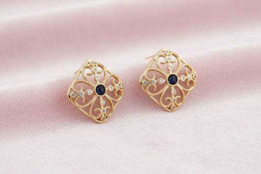 Gold filigree stud earrings with navy lapis lazuli center stone and mother-of-pearl accents in ornate quatrefoil design
