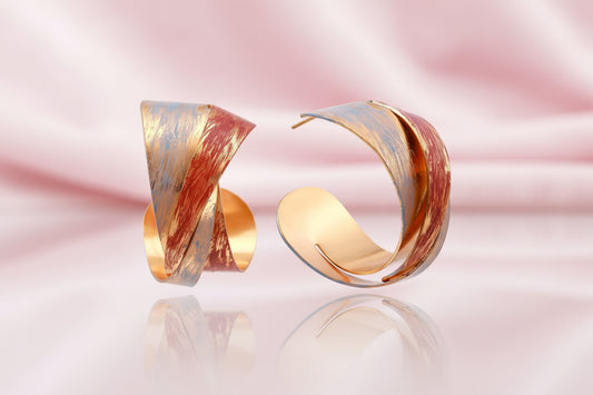 Sculptural gold-plated hoop earrings with diagonal purple and coral enamel stripes in twisted ribbon design