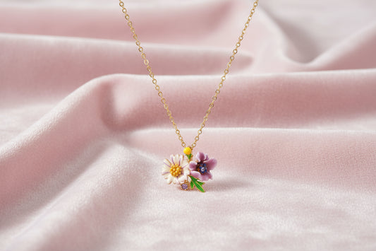 Gold-plated necklace with pink and purple enamel flower pendant featuring crystal accents on cream background