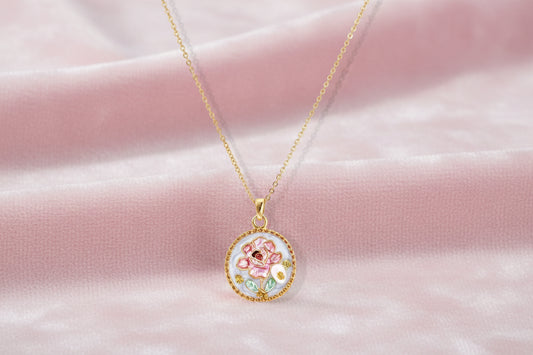 Gold-plated circular pendant with pink enamel rose, pearl background, and delicate beaded border on chain
