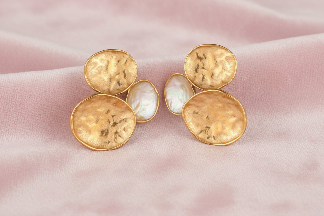 Three hammered gold discs clustered together forming organic statement earrings with textured surfaces