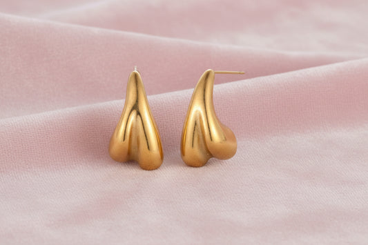 Organic sculptural gold stud earrings with fluid matte finish on cream background