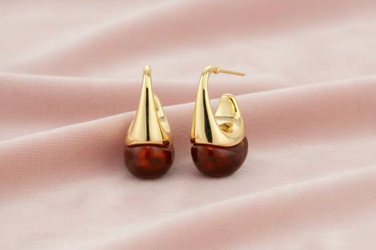Modern drop earrings with curved gold-plated copper tops and amber resin bottoms creating an organic teardrop silhouette.
