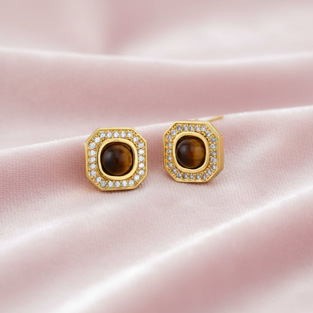 Gold-plated octagonal stud earrings with brown tiger's eye centers and cubic zirconia border on cream background.