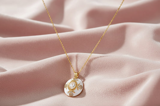 Gold-plated necklace with circular white enamel pendant featuring central zirconia stone and ornate decorative details