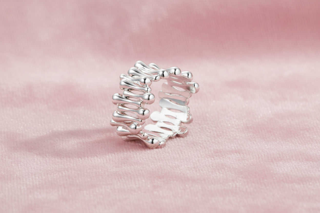Wide band ring with sculptural wave ripples in polished white gold plated eco-brass on cream background