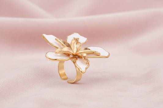 Gold-plated sculptural ring featuring white enamel petals forming an oversized lily bloom on adjustable band