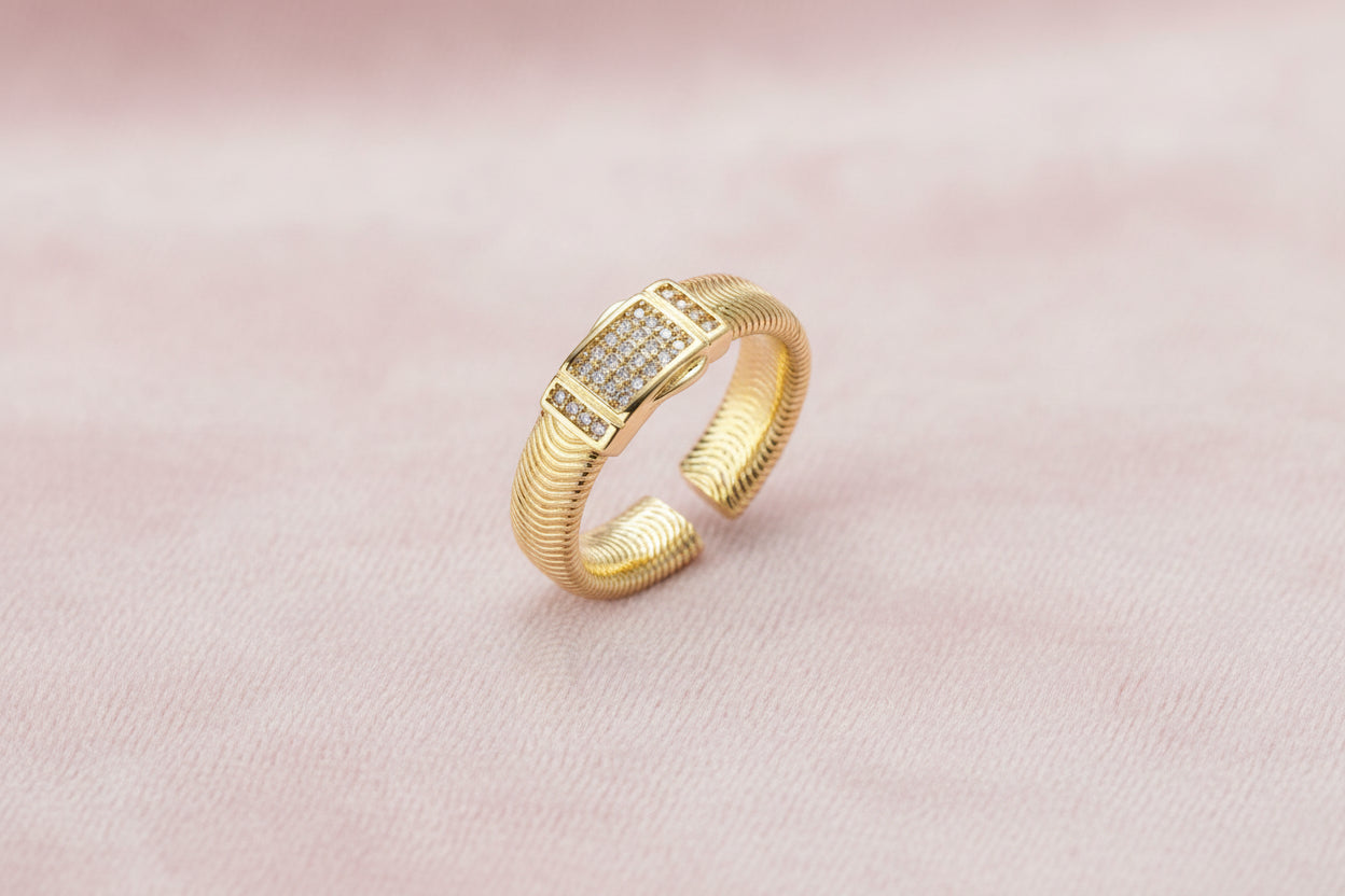 Gold-plated adjustable ring with ribbed band and rectangular pavé cubic zirconia panel on white background.