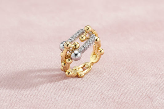 Triple-band gold ring with spherical bead chains and two crystal-pavé bars on cream background