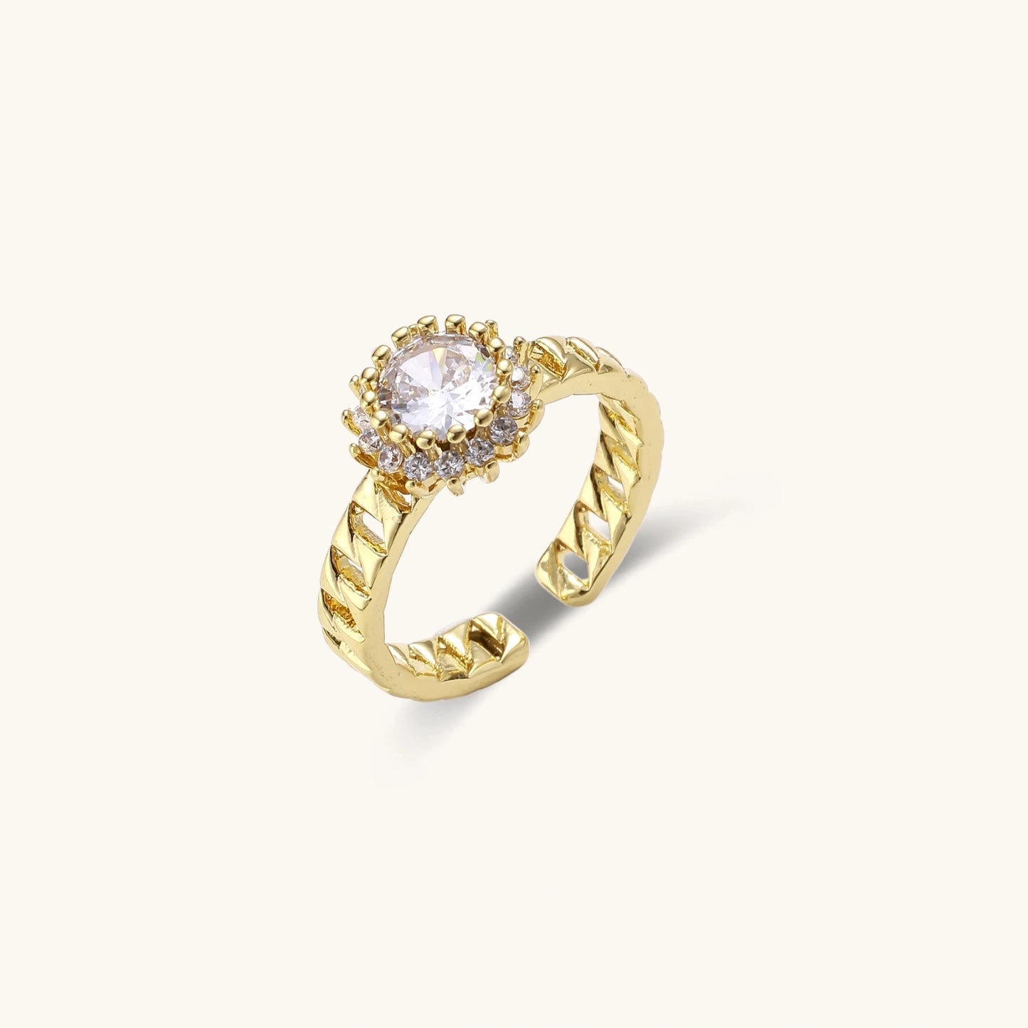 Gold-plated adjustable ring with twisted chain band, central cubic zirconia stone surrounded by crystal halo on cream background