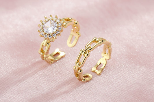 Two adjustable gold rings: chain-link band and halo-style ring with cubic zirconia stones on cream background